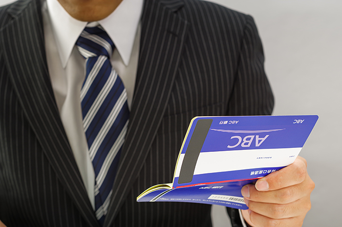 通帳を持つスーツの男性