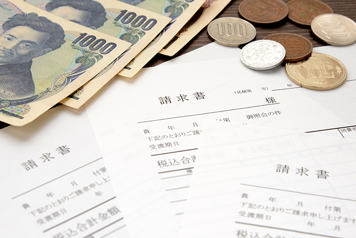 請求書とお金が散らばっている