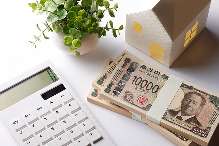 家の模型と札束と電卓が置いてある